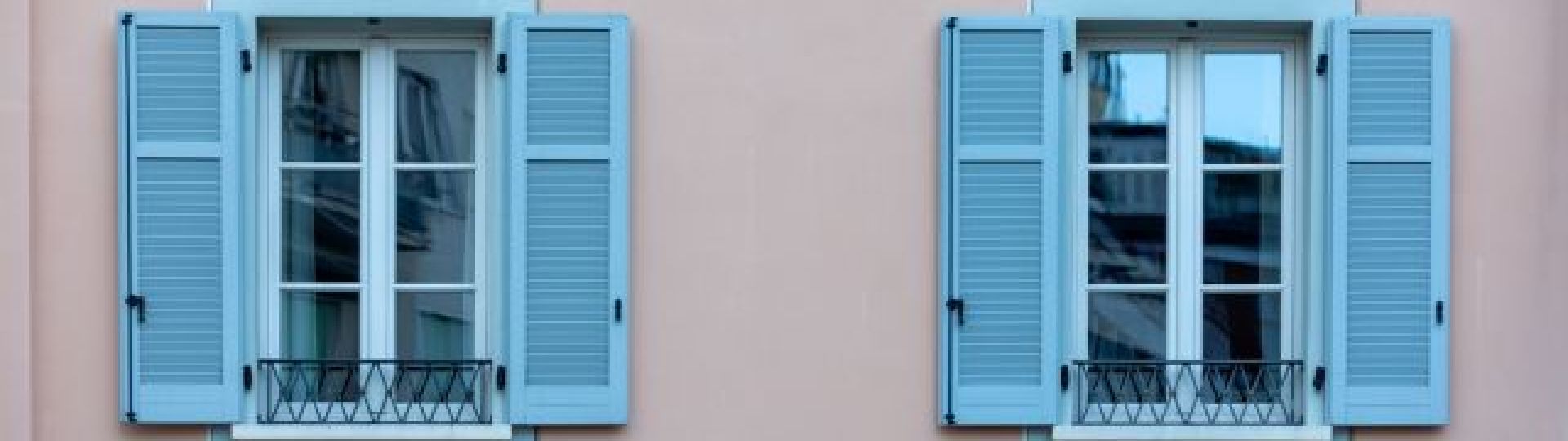 Blue shuttered French windows on a pink building in France
