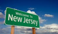 'Welcome to New Jersey' green sign against a blue sky with clouds