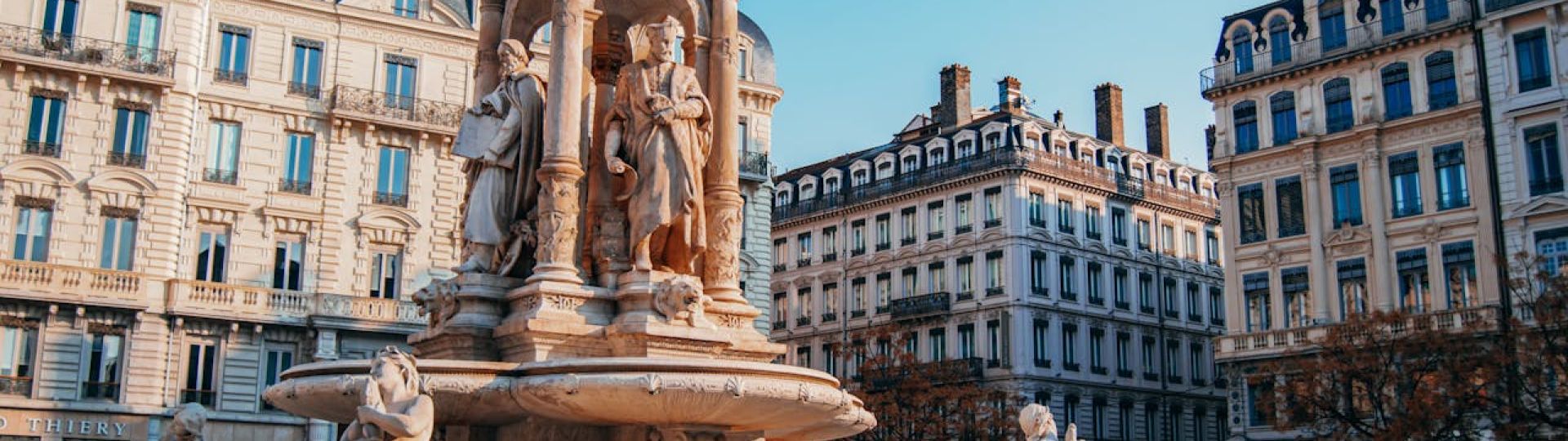 An ornate fountain surrounded by 19th century buildings in a square in Lyon, France