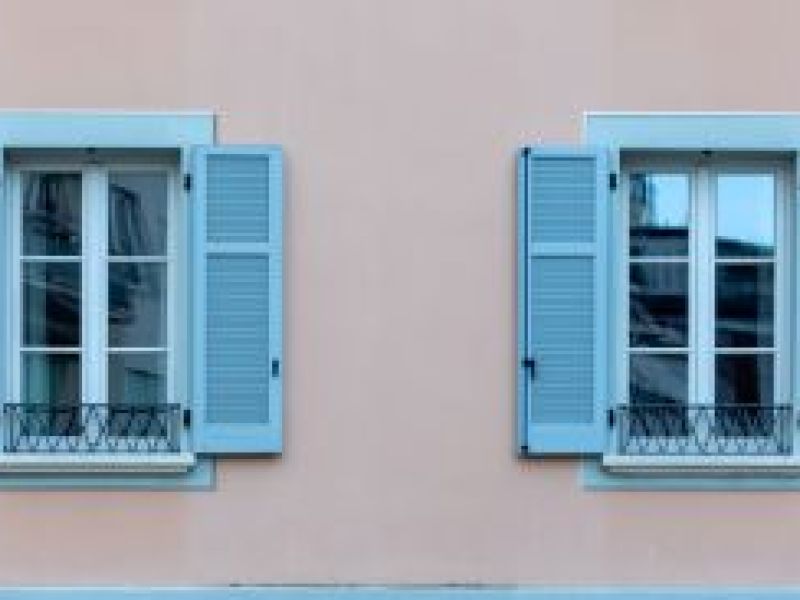 Blue shuttered French windows on a pink building in France