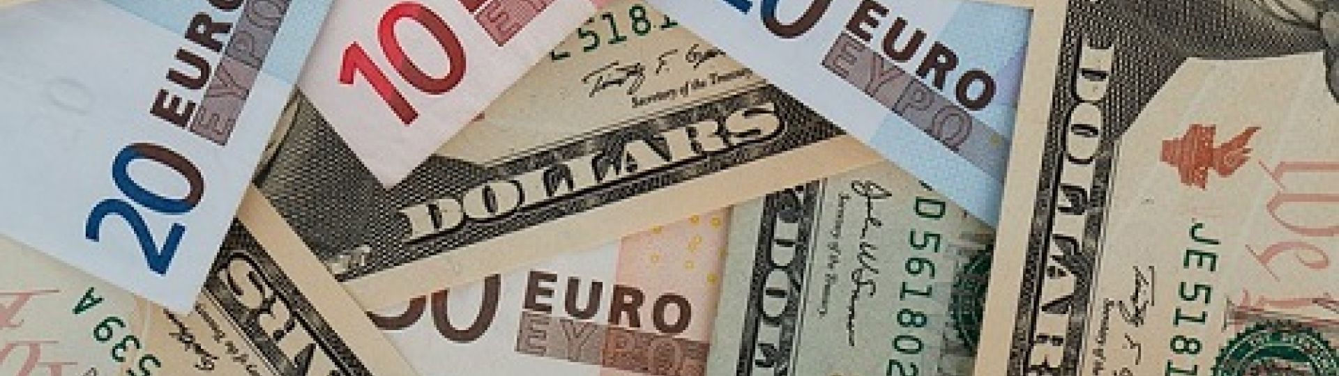 A stack of paper money from various currencies, including euros and dollars