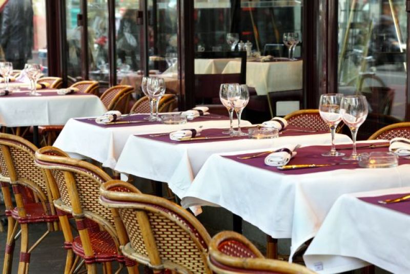 Line of white-tableclothed tables in a French restaurant terrace