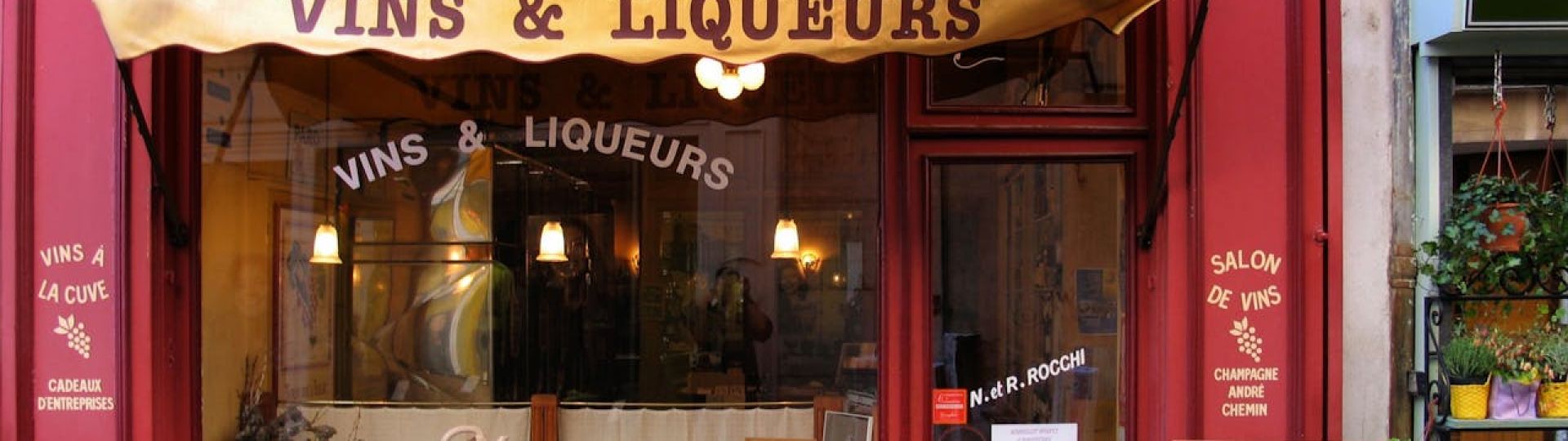 The front of a business in France selling wines and liquers, with red walls and yellow signage